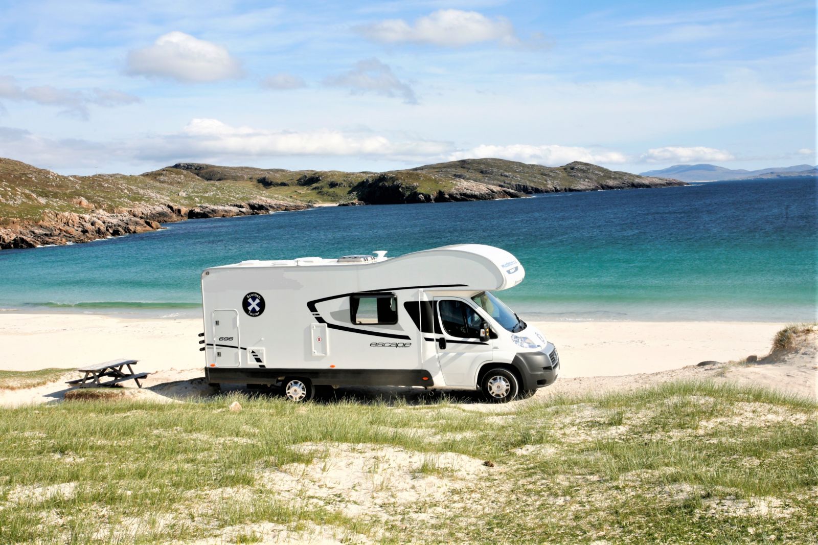 campervan parked in front of a beautiful Scottish white sand beach